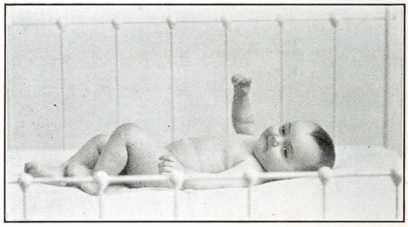 A baby laying on its back with one
arm raised